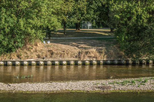 Hitzeschaden verdorrtes Gras an Uferb&ouml;schung und Kiesbank  wegen Niedrigwasser am Ermszufluss in den Fluss Neckar in Neckartenzlingen