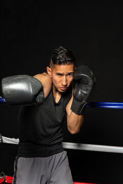 Hispanic boxer throwing powerful right punch toward camera on black background