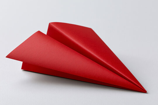 Red paper airplane on a flat surface