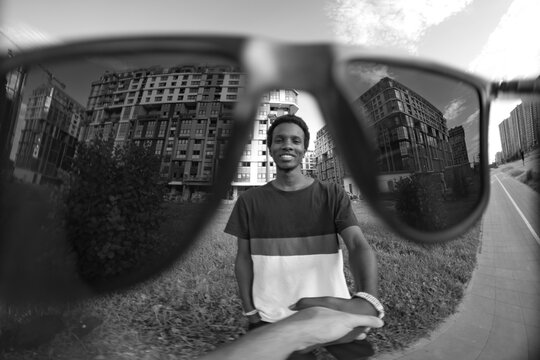  Black and white POV portrait of smiling man looking through sunglasses with copy space