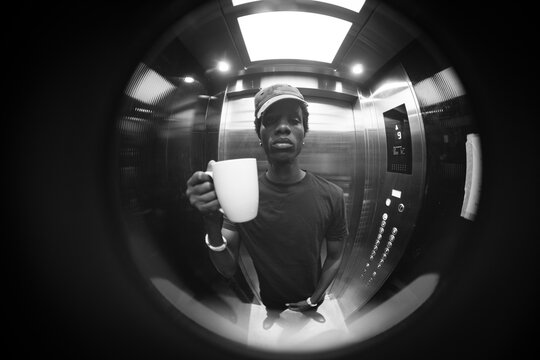 Circular fisheye black and white portrait of man with coffee cup in elevator with copy space