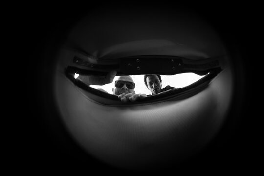 Inside bag POV of two men opening zipper with concrete copy space