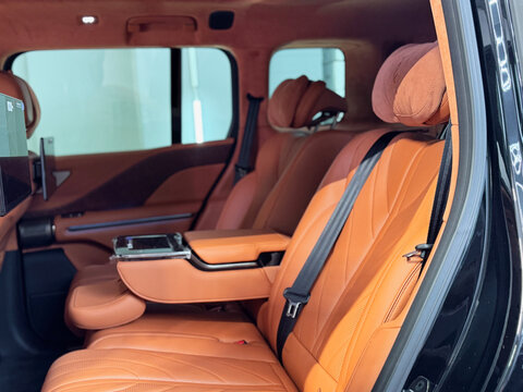  Luxurious orange brown leather interior of BYD Yangwang U8 hybrid SUV inside a detailing studio. Premium rear passenger seats with premium upholstery, alcantara headliner, advanced armrest controls. 