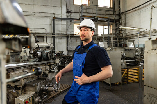 Professional Machinist Standing by Industrial Machine in Factory