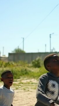 Vertical video: Running boy in gray 92 hoodie tracking lobbed ball, preparing to head on sandy lot