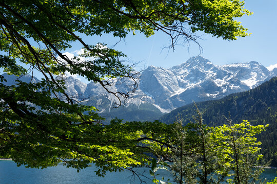 Travel landscape of Eibsee lake and Zugspitze mountain peak in Alps in Bavaria, Germany, scenic summer nature panorama with forest und mountains. Alpine landscape
