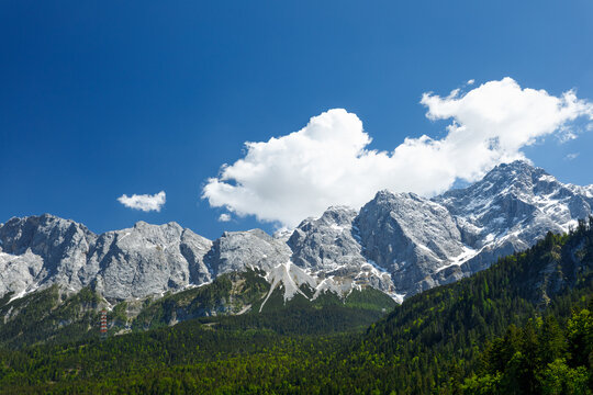 Travel landscape of Zugspitze Alps in Bavaria, Germany, scenic summer nature panorama with forest, snow mountains peak. Alpine landscape