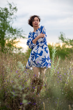 Woman in Blue Floral Dress Standing in Wildflower Field