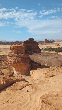 Sun shines to rocky desert landscape near Al Ula, view around from higher sandstone formation viewpoint near Vessel Hole Rock, vertical video