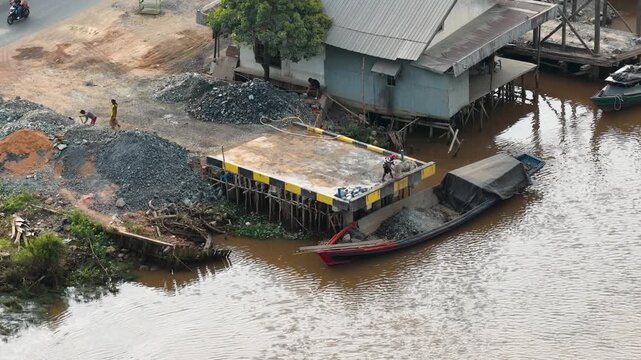 operating a hose to clear sand on a sand-carrying vessel on the Banjarmasin River
