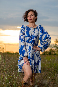 Woman in Blue Patterned Dress at Sunset in Meadow