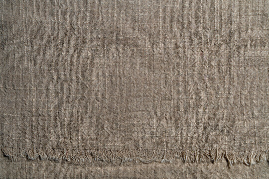 Natural coarse linen fabric texture background with frayed edge. Rustic burlap sackcloth textile background rough canvas organic flax material design concept, copy space