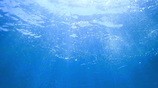 Light filtering down through blue water. Underwater sunlight in deep sea. Light viewed from blue abyss. Underwater sunlight shining deep with ripples on wave surface ocean ray, Under water Slow motion