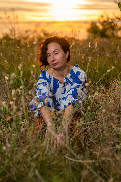 Woman Sitting in Meadow at Sunset