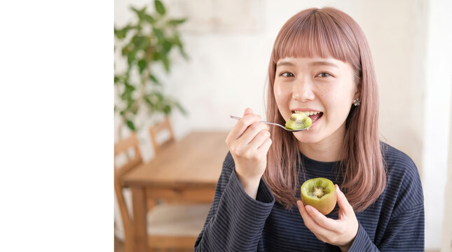 満面の笑みでキウイフルーツを食べる若い女性