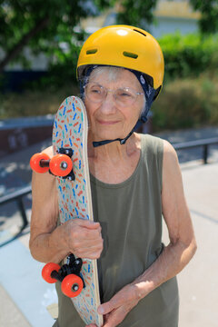 Elderly woman holding her skateboard in skate park