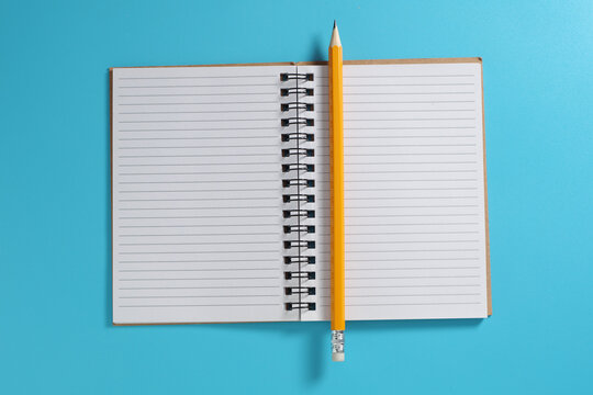 Open spiral notebook with pencil