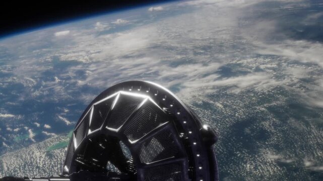 A black and silver structure spins in space. Below is the blue and green planet Earth with clouds visible in the atmosphere. This scene captures the view from orbit.