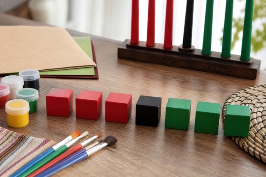 Seven red, black and green wooden blocks with art supplies and kinara for a hands free Kwanzaa learning activity and family education