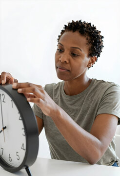 African american woman adjusting a black and white analog clock, time management and punctuality