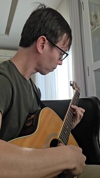 homem tocando viol&atilde;o acustico em casa 