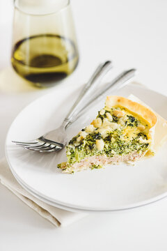 Delicious broccoli and cheese quiche slice with fork and glass of drink
