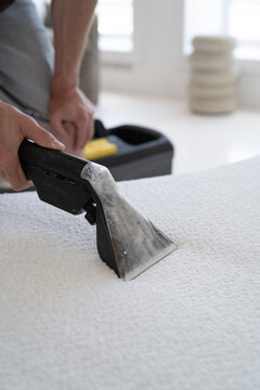 Close-up of professional vacuum extractor nozzle cleaning white plush textile with visible dirty water.
