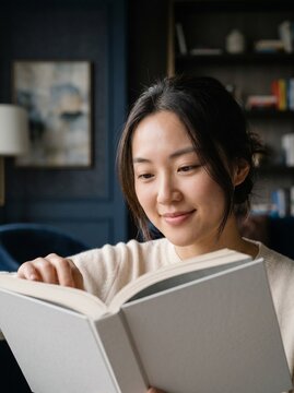 Closeup of Asian woman reading book with soft smile