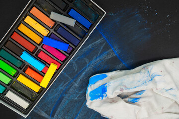 Chalk pastels and a stained cloth lie on a blackboard with blue markings © Floren Horcajo