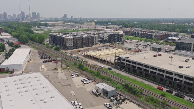 Drone aerial of new building construction of parking garage structure being structured and built by contractor crew at modern apartment complex for rental property tenants to park cars and vehicles 4k