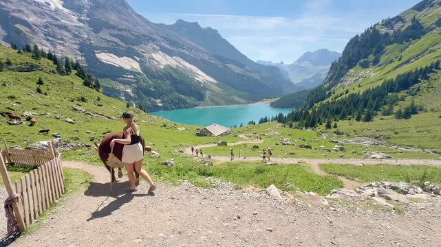 Oeschinen Lake, Switzerland - August 14, 2026: Tourists hiking along the lake with views of the Swiss Alps
