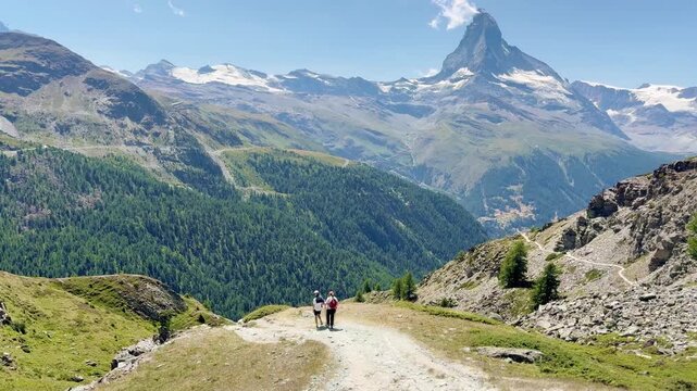 Tourists hiking along the lake with views of the Swiss Alps