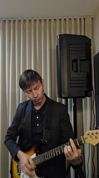 homem musico tocando guitarra em est&uacute;dio casa