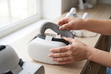 Fototapeta premium Person holding and inspecting the grey fabric strap of a VR headset