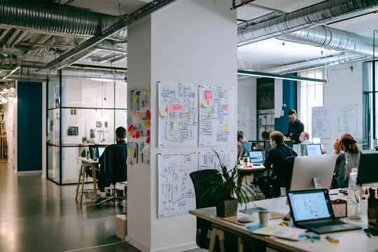 The startup office features a whiteboard displaying lean canvas along with flow diagrams, all used during a creative brainstorming session