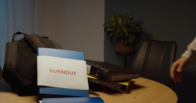 Overworked employee throws binders onto a desk due to excessive workload and burnout. Ideal for work stress, overload, exhaustion and workplace pressure.