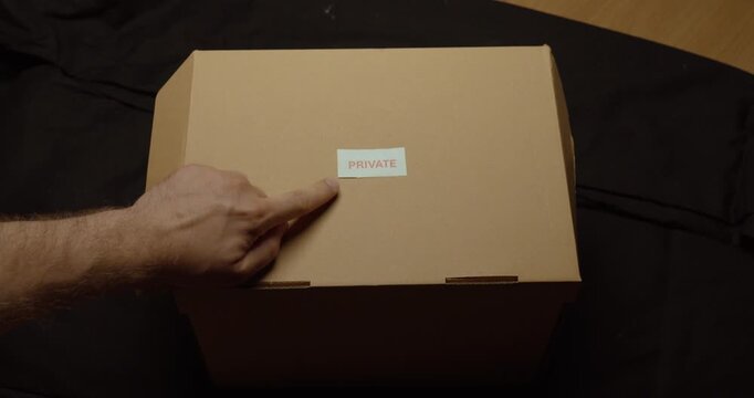 Person placing a Private label on a cardboard box. Ideal for privacy, confidential items, restricted access, personal documents and secure storage.