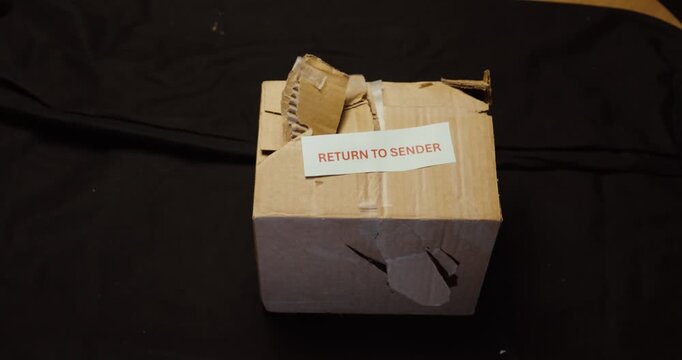 Person holding a damaged parcel marked Return to Sender. Ideal for shipping damage, failed delivery, returns, logistics and damaged goods.