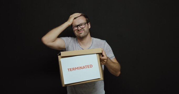 Upset man holding a box marked Terminated after losing his job. Ideal for dismissal, unemployment, layoffs, job loss and career crisis.