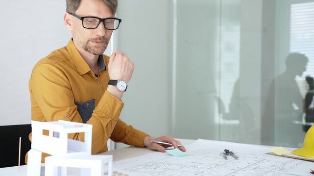 Professional architect designing a new building project, planning with blueprints and a scale model in a modern office, developing urban structures and innovative construction ideas