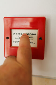 Hand breaking fire alarm glass during emergency