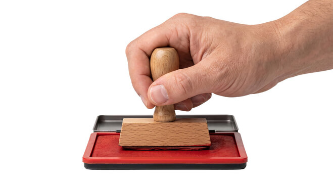 Hand holding a wooden stamp over a red ink pad for official approval