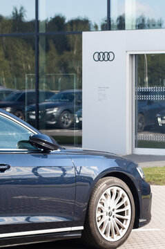 Riga, Latvia - August 8, 2026: The photo shows an Audi car on the street near the Audi auto center. The Audi logo of four rings is on the building of the auto center.