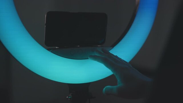 Fingertip and hand interact with illuminated circular LED ring, touching and hovering along inner edge as colors shift through blue, cyan, green, pink, red, and yellow