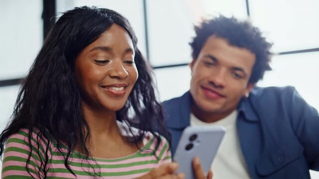Diverse couple looking smartphone sitting home closeup. Man woman ordering goods