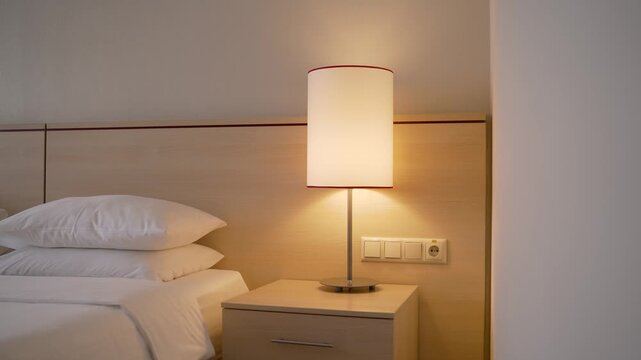 Modern hotel bedroom with lit table lamp and white bedding