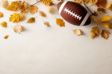 Fototapeta premium A brown football rests among scattered autumn leaves on a light-colored surface.