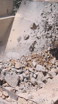 Unloading of stone from the truck to the stone crushing machine at open pit mining and processing plant for crushed stone, slow motion. Concepts of industry and building materials, sand and gravel