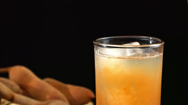 Refreshing agua de Tamarindo with ice and whole tamarind fruit