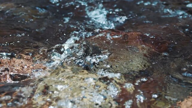 Cool summer river water flowing over rocks in slow motion
